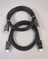 Two black HDMI cables coiled and secured with twist ties, metal connectors visible with HDMI markings