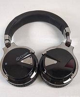 Front view showing black Cowin Bluetooth wireless headphones with silver triangular control accents on each ear cup, padded headband, and adjustable hinges.