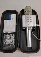 Photo of karaoke microphone inside black hard zippered case with user manuals and cables