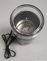 Top view of the coffee grinder showing the stainless steel blade inside the grinding chamber with a clear plastic lid.