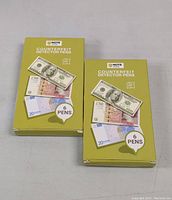 Two unopened yellow-green boxes of Note brand Counterfeit Detector Pens, each box containing 6 pens for detecting fake bills.