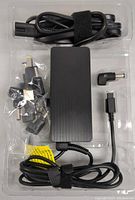 View of contents including rectangular power adapter, AC power cable, USB-C cable, and several interchangeable charging tips.