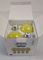 Open box showing three yellow dome LED bulbs with screw bases inside a white Dewenwils branded box.