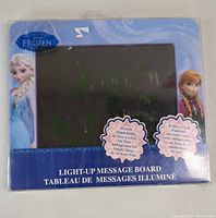 Frozen-branded light-up message board in original blue packaging, showing Elsa and Anna characters on sides with LED message board visible.