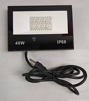 Front view of the black rectangular IP66 40W LED light with a visible power cord and plug.