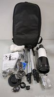 Full lot contents laid out including telescope tube, tripod, backpack, instruction manual, eyepieces, phone adapter, compass, and mounting hardware.