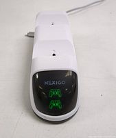 Front view of white charging dock with glossy black panel displaying NexiGo branding and green LED controller icons indicating two charging ports.
