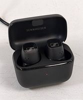Front angled view of black Sennheiser CX Plus TW1 C earbuds inside their open charging case with Sennheiser logo visible.