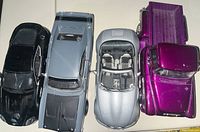 Top view of five die cast cars showing size and colors: black Aston Martin, gray Dodge Charger, silver BMW convertible, purple Chevrolet pickup, and blue Chevrolet car.