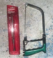 Close-up of package containing 5 Husky spade saw blades next to the same coping saw.