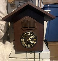 Front view of the vintage wooden cuckoo clock showing the Roman numeral face and closed cuckoo doors.