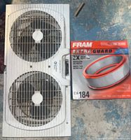 Top view of twin exhaust window fan and boxed Fram engine air filter on floor