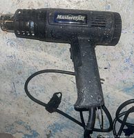 Side view of the black Mastercraft heat gun showing the logo on the side, the handle, and power cord.