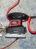 Jobmate finishing sander laying on the ground showing top and front side with power cord and Jobmate logo