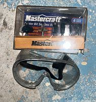 Router bit set and safety goggles shown in original packaging on a blue surface