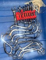 Top-down view showing 9 Angel wrenches secured in red plastic holder alongside 8 assorted mechanical wrenches scattered below.