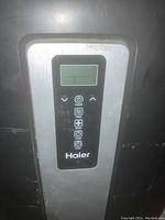 Close-up of the digital control panel showing the Haier branding and operational buttons.