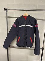 Front view of the men's black coat with red accents, zip-up closure, reflective strip across chest, and patches on sleeves.