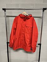 Front view of the men's red hooded coat showing zipper, chest pocket, side pockets, hood, and adjustable cuffs.