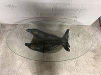 Top-down view of oval glass tabletop and dolphin sculpture base
