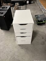 Top view of the white cabinet showing five drawers with curved recessed handles.