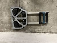 Folded metal folding handtruck with blue and black handle resting on gray surface