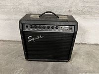 Front view of the black Squier Champ 15GRII guitar amplifier showing control panel and speaker grill.