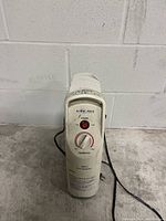 White compact oil-filled radiator heater with power knob and red power indicator light on the front panel.