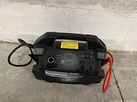 Front view of the Motomaster Eliminator Powerbox showing display, jump start cables, power outlets, and control features.