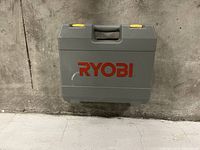 Closed grey plastic carrying case with red Ryobi logo and yellow latches