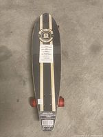 Top view of new wooden skateboard deck with black and natural wood stripes, MADD GEAR branding near nose, and red wheels.