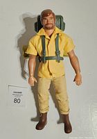Front view of Big Josh action figure wearing yellow shirt, pants, brown boots and green backpack