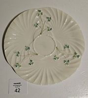 Top-down photo showing the full round ivory serving platter with scalloped edges and green shamrocks spaced symmetrically on the surface.