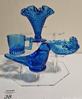 Lot of four blue Art Glass items including hobnail vase, Bluebird of Happiness, cup, and ashtray