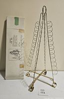 Front view of brass card tree display holder next to original box with printed instructions