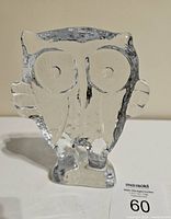 Front view of clear glass Kosta Boda owl sculpture showing large round eye shapes and detailed beak on thick glass base.