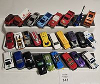 Image showing 24 loose diecast cars on display shelves, featuring various colors and vehicle types including trucks, sports cars, SUVs, and utility vehicles.
