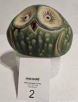 Front view of the green pottery owl figurine showing carved eyes, beak, and speckled glaze.