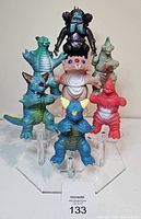 Front view of seven vintage kaiju and robot figures on display stand