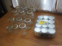 Assorted clear glass canning jars in various sizes and conditions arranged on table.