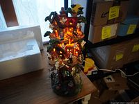 Front view of the illuminated haunted tree house Halloween decoration on a wooden surface.