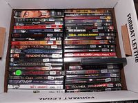 Top-down view of a box filled with various horror DVD cases showing spines with titles.