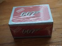 Photo of the small sealed rectangular box game with red top and white border edges, showing 007 logo and Trivia USA branding.