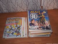 Stack of Mad Magazine issues with one Cracked stack visible alongside on wood surface