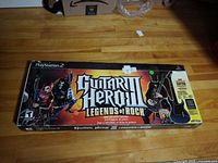Closed box showing Guitar Hero III Legends of Rock branding for PlayStation 2 with character artwork and guitar controller image