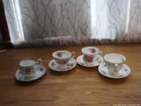 Four Royal Albert teacups each paired with a saucer plate displayed on a wooden surface with natural light background.