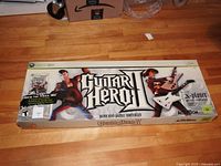 Front of the Guitar Hero II box for Xbox 360 showing game title and guitars illustrations.