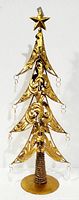 Gold metal Christmas tree with decorative scrollwork and tear drop accents, standing on a round base with a star on top.