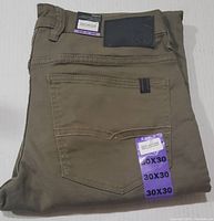 Folded tan Buffalo David Bitton jeans laid flat showing back pocket with 30x30 size sticker, leather brand patch and stitching details.