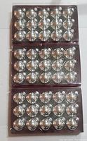 Photo showing three boxes of silver spherical glass ornaments. Each box contains 15 ornaments arranged neatly in individual plastic slots.